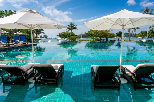 Hotelpool mit Liegen im Wasser und blauem Himmel